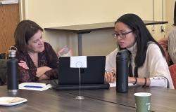 Two women sit at a computer discussing mentoring