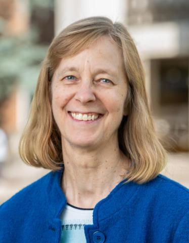 headshot of a woman with short blonde hair cut into a bob and wearing a blue cardiagan.